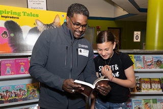 A volunteer helps a child pick out books at a book fair
