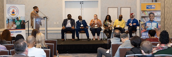 Panel discussion speaker holding microphone with panelists in background