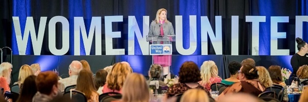 Woman speaking to audience in front of large letters that say Women United