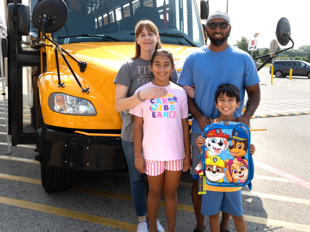 Image of family with backpack in front of bus