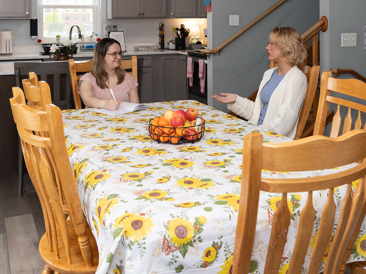 Two women sitting at a kitchen table talking to each other