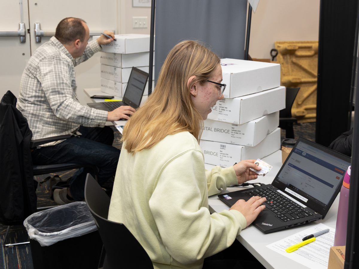 Volunteer help set up laptops during a distribution event.