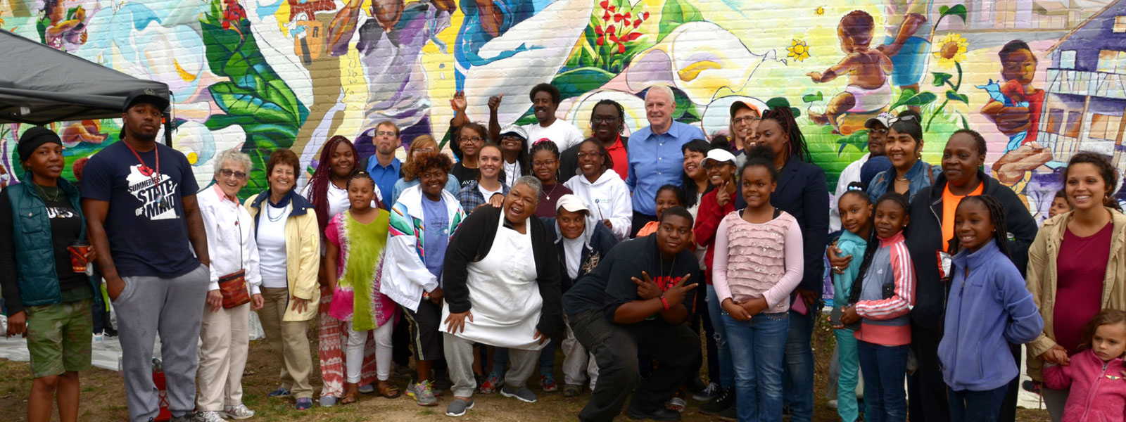 large group of people standing in front of mural