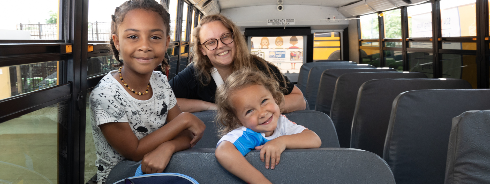 two girls with backpacks in front of a school bus