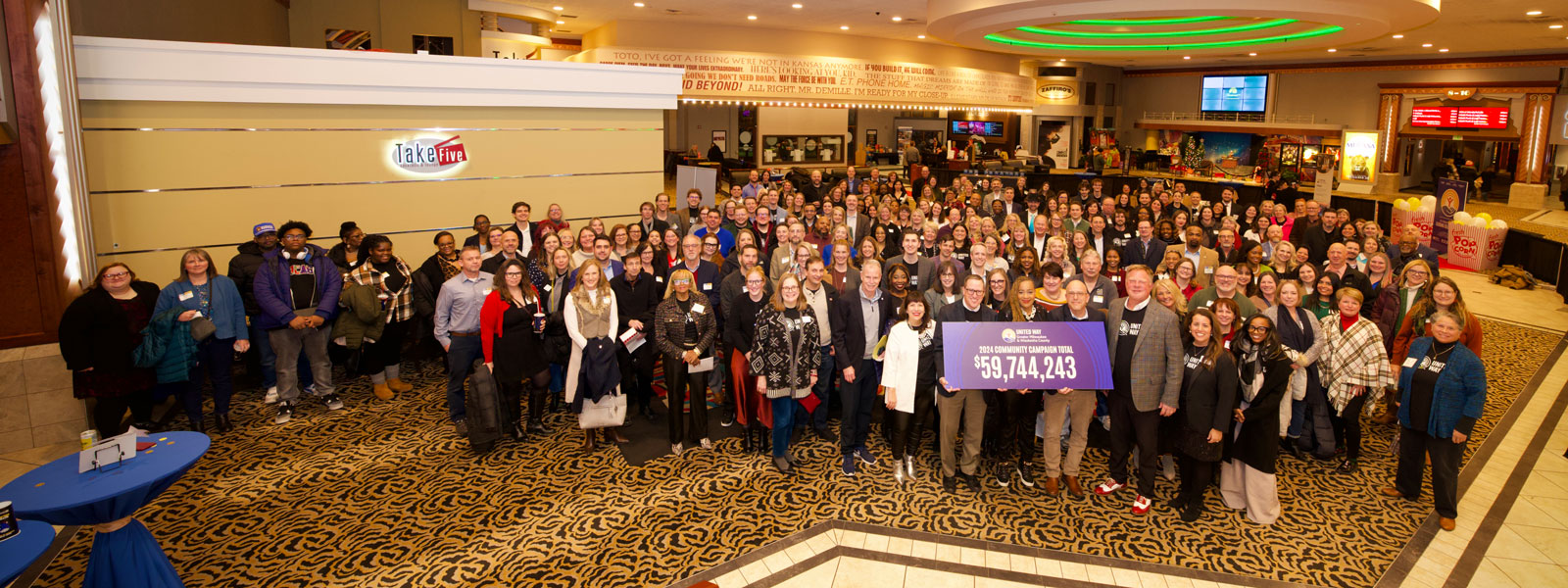 large group of people holding a sign that says 2024 community campaign total, $59,744,243