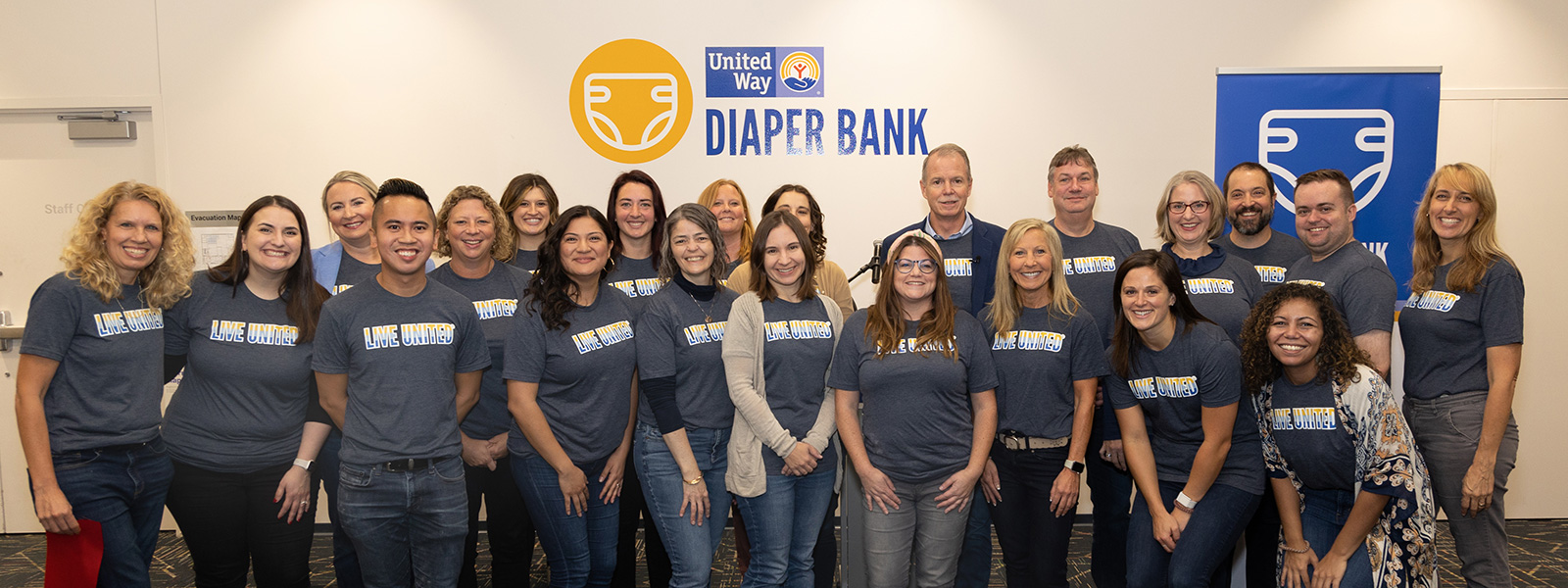 group of volunteer posing for photo by Diaper Bank sign