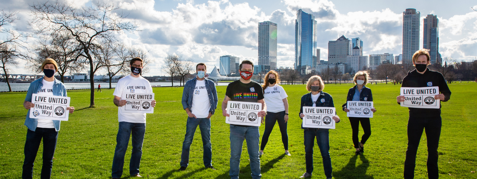 LINC members holding Live United signs outside with the Milwaukee skyline in the background.