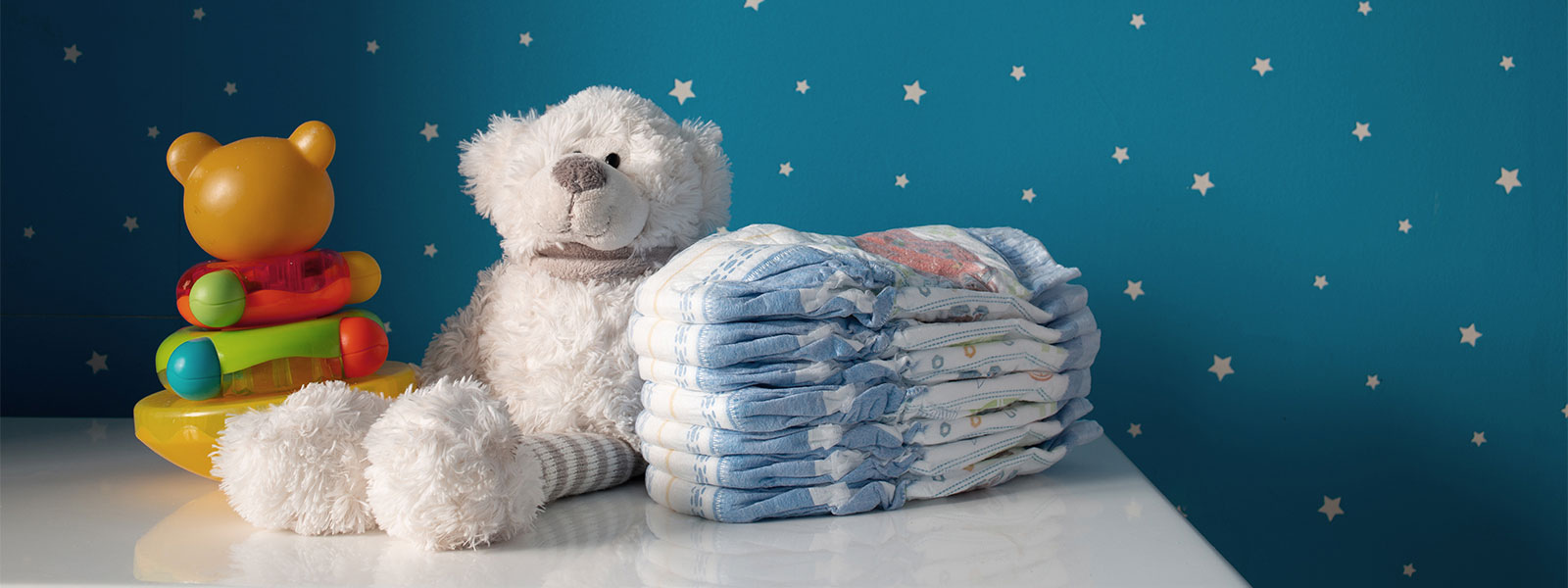 teddy bear and diapers stacked on a dresser