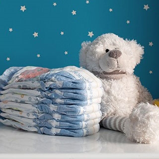 Teddy bear with stack of diapers on changing table