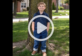 Little boy in front of free with overlay play button