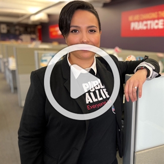 Image of women with a Public Allies shirt on standing in an office