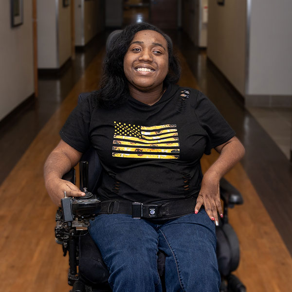 A picture of seria, a young woman in a wheelchair smiling.
