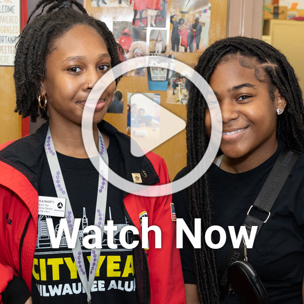 Image of two youth by door with overlay play button