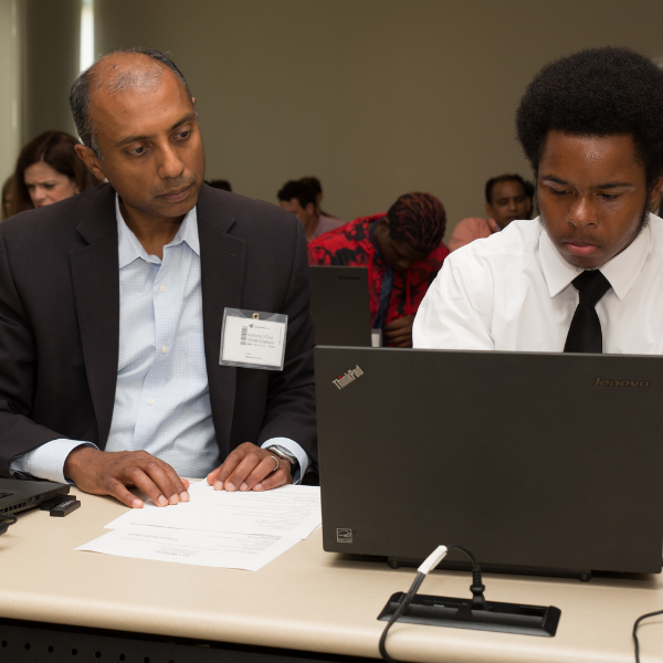 A volunteer and an attendee at the Men's Job Seminar working together at a laptop.