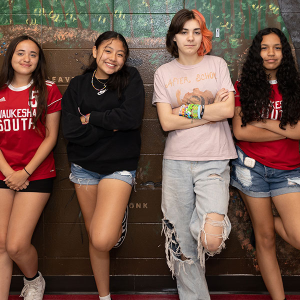 group of high school student leaning against a mural