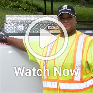 image of woman in construction vest in front of truck with a play overlay button