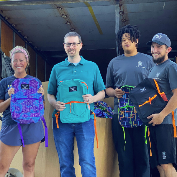 Karissa Gretebeck of United Way and a TWO MEN AND A TRUCK team pose with backpacks